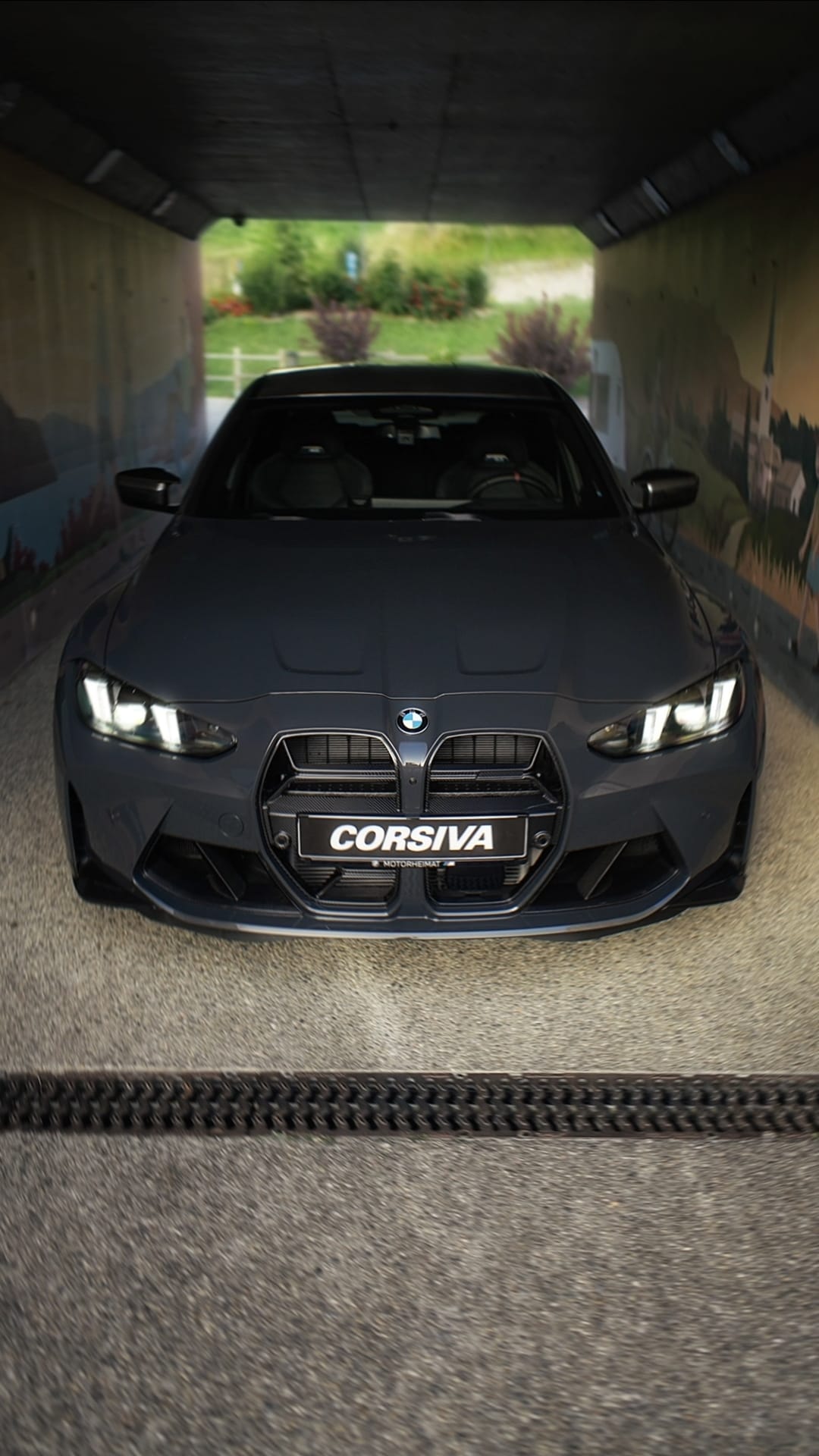 BMW M3 Corsiva de face, phares allumés, plaque CORSIVA